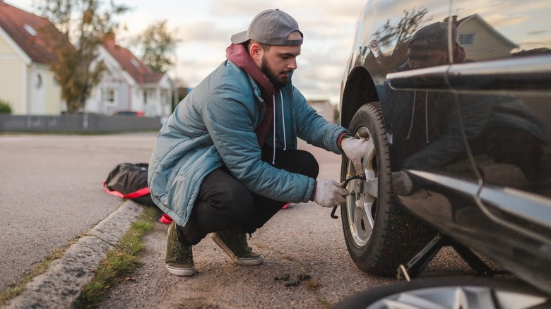tire-blowout-warning-signs-2-man-changing-a-flat-tire