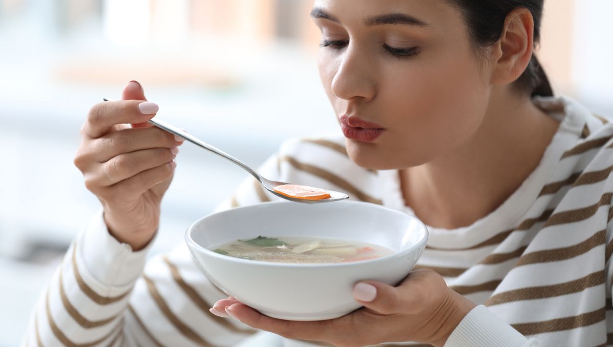 woman-blowing-on-a-spoonful-of-vegetable-soup-meta