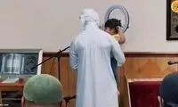 یک کودک در آغوش امام جماعت در حال اقامه نماز