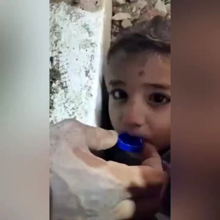 آب دادن به یک کودک که نیمی از بدنش زیر آوار بود