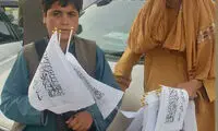 کودکان دستفروش در حال فروش پرچم طالبان